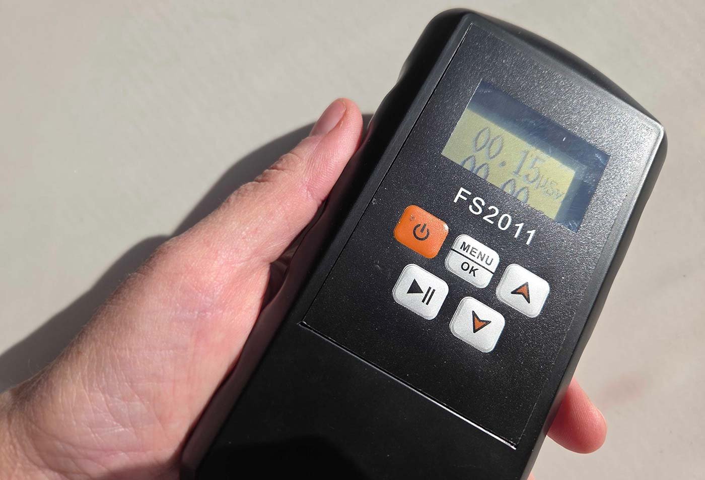 A hand securely holds a Geiger counter displaying numerical readings, illustrating practical applications in ASU's Nuclear Engineering program.