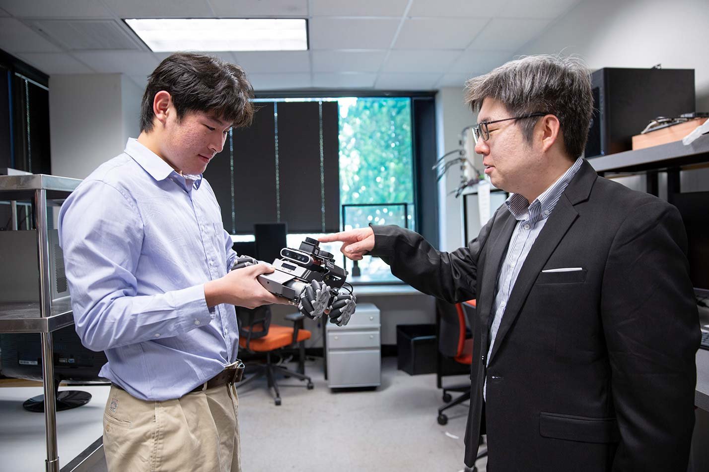 A faculty member reviews a robotic hand prototype with a student in ASU's Robotics and Autonomous Systems (Electrical Engineering), MS program.