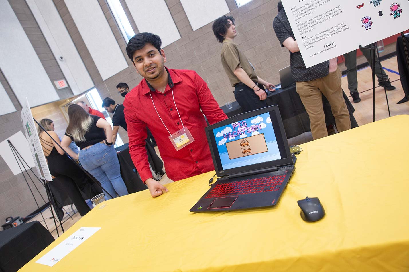 A student demonstrates his project in an exhibit hall, demonstrating practical learning in the Computer Gaming certificate.