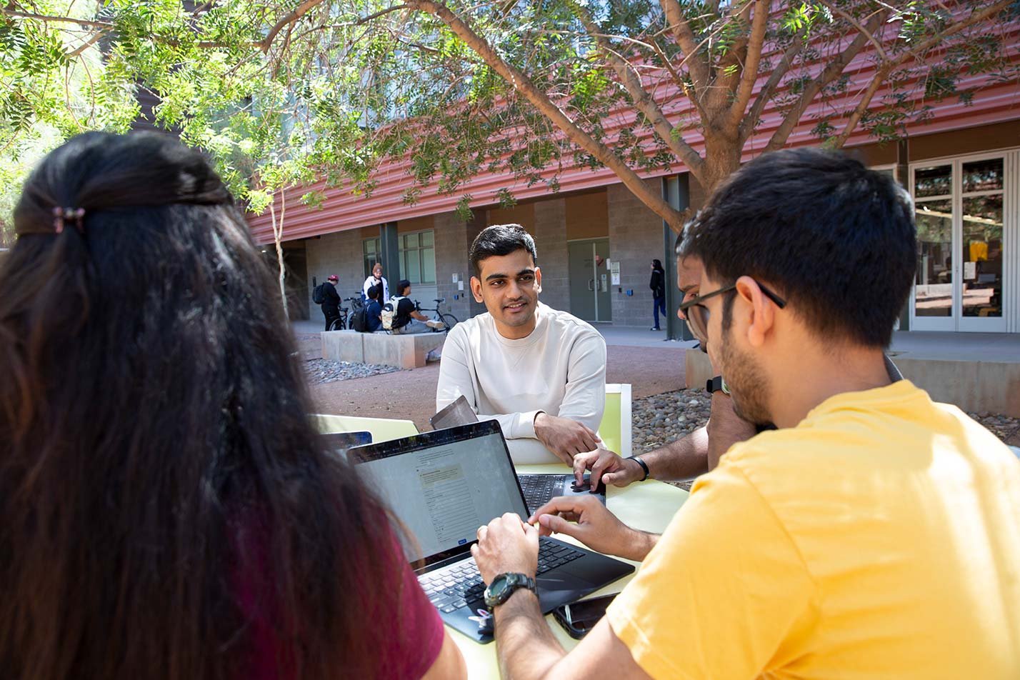 Students collaborate outdoors with laptops, highlighting teamwork in ASU's Engineering Science (Software Engineering), MSE program.
