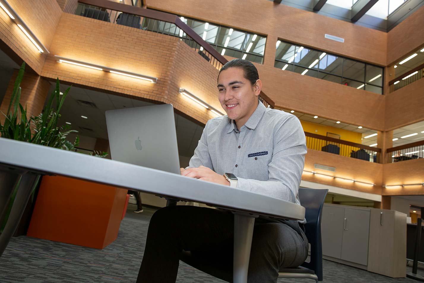 A student works on a laptop at a table in Noble Library, reflecting engagement in ASU's Applied Ethics and the Professions degree.