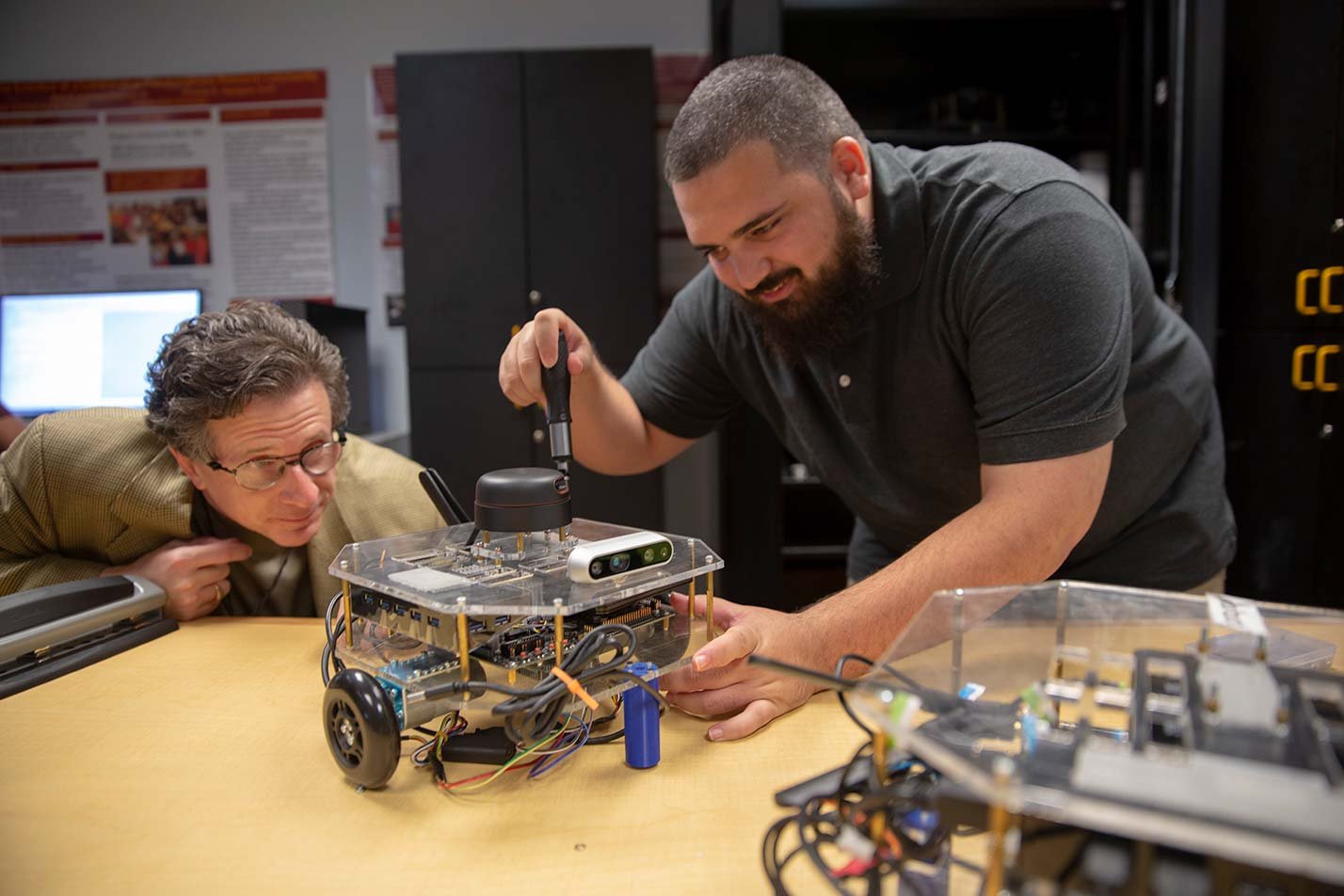 A professor observes as a student builds a transparent robot, showcasing collaboration in ASU's Mechanical Engineering Systems program.