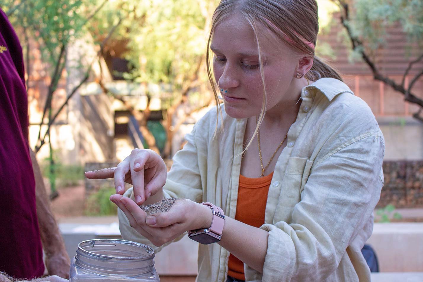 A student shifts gently through soil outdoors, highlighting practical learning experiences in ASU's Environmental and Resource Management degree.