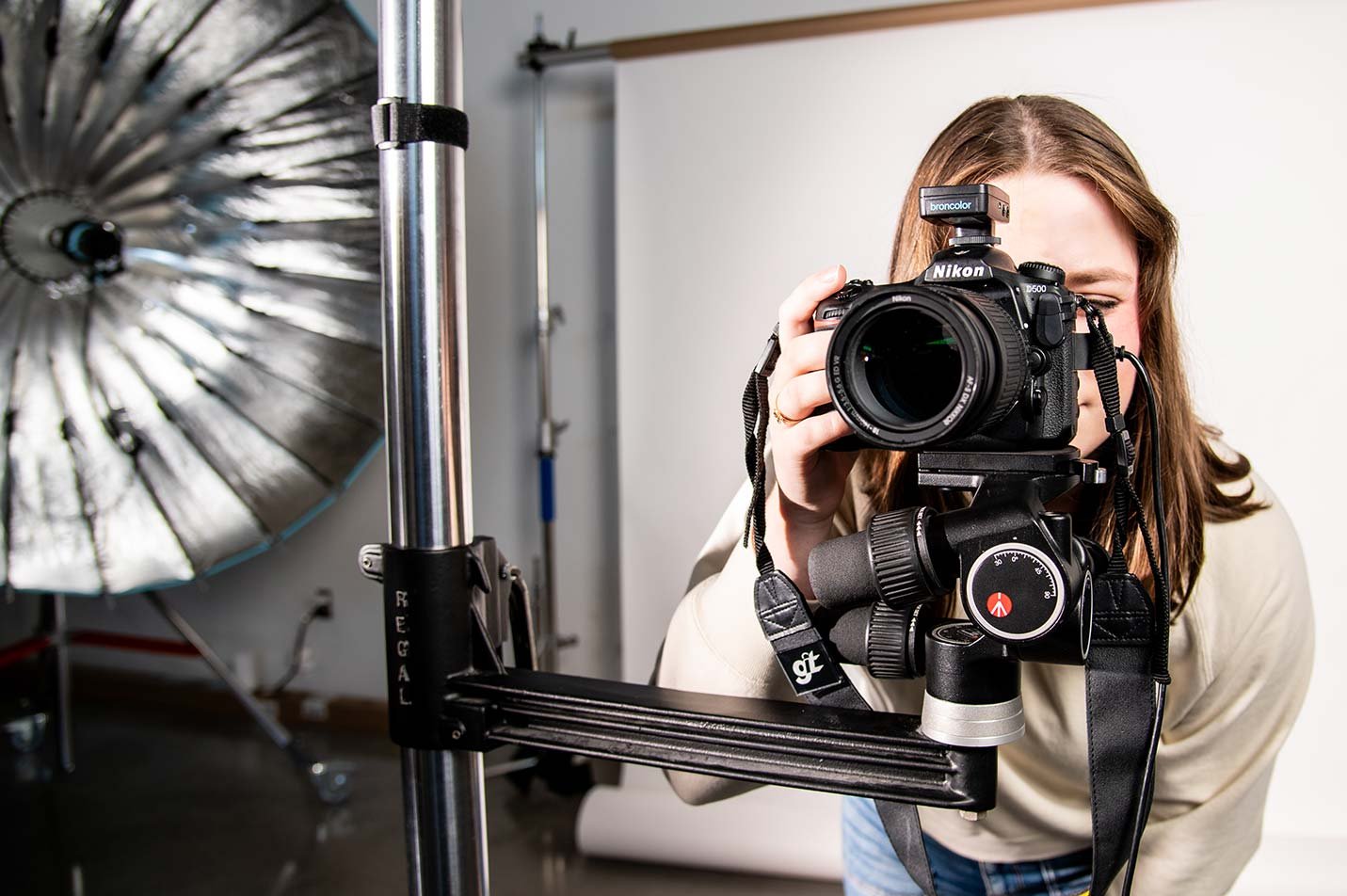 A student photographs with a camera in a well-equipped studio, showcasing practical skills in ASU's Graphic Information Technology program.