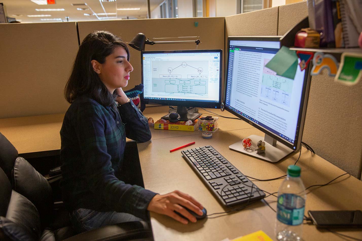 A student engages with dual monitors, analyzing programming tasks, reflecting her studies in ASU's Information Technology program.