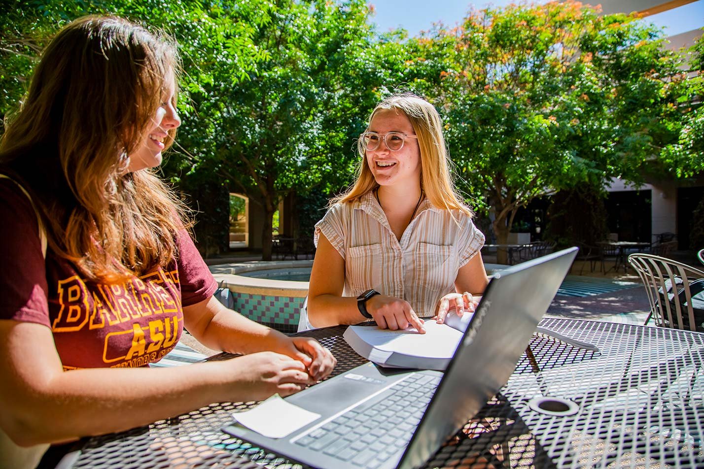 A team brainstorms ideas on a outdoor table, reflecting collaborative problem-solving in ASU's Information Technology, MS program.