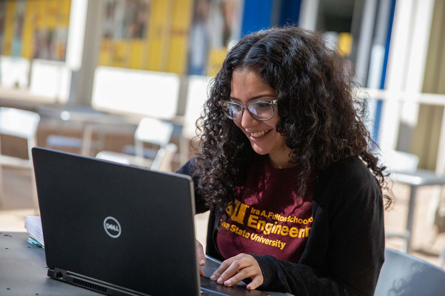 A student smiles while working on her laptop, highlighting real-world applications in ASU's Applied Science (Internet and Web Development) program.