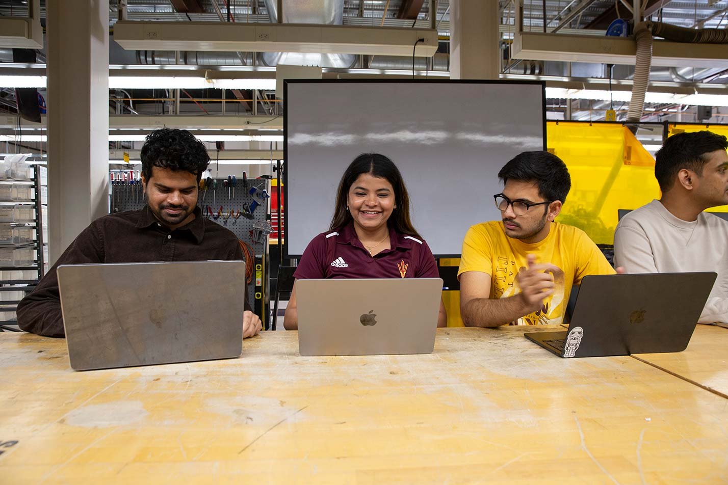Students collaborate on laptops in a makerspace, reflecting teamwork in ASU's Software Engineering, MS program.