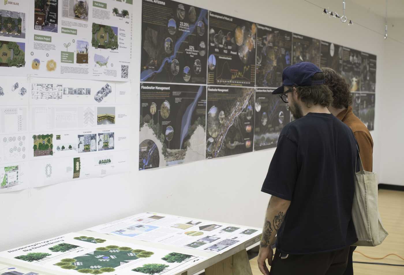 Two students review posters showcasing design created by landscape architecture students, showcasing the work done in the minor in Landscape Studies.