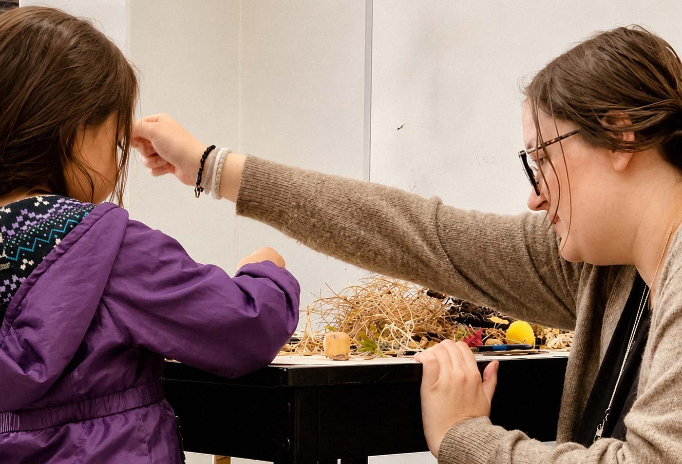 An ASU student assists a young child with arts and crafts, showcasing the field explored in the BFA in Art (Art Education).
