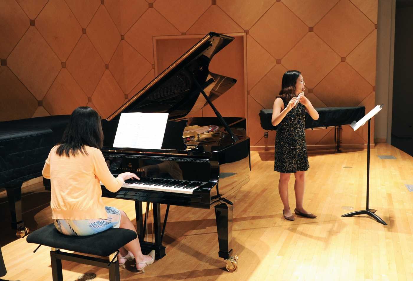 A pianist plays alongside a flutist on a stage, showcasing hands-on learning in the Performance (Collaborative Piano), MM.