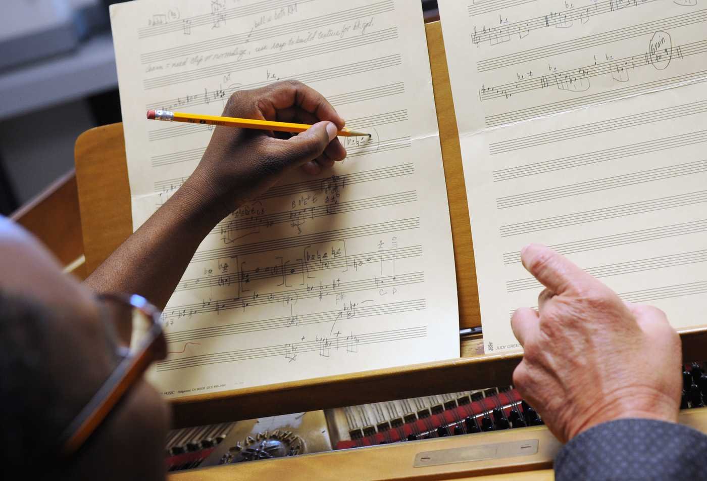 A student takes notes on a music sheet, showcasing hands-on learning in the Composition, MM.
