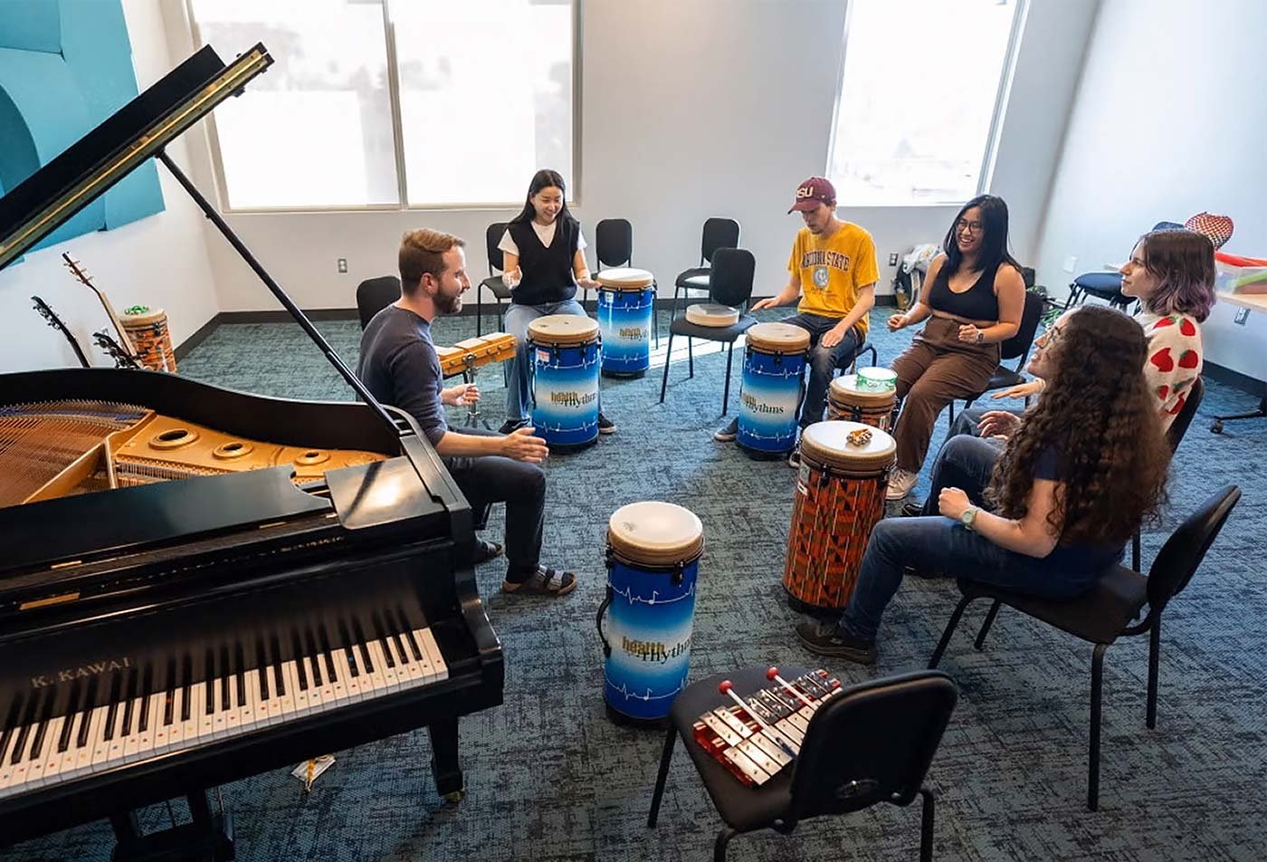 Students play drums together, showcasing hands-on learning in the Music Therapy, MM.