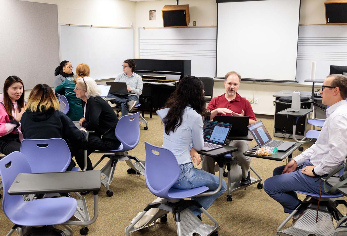Students collaborate in small groups around a musical classroom, showcasing collaborative learning in the Music (Music Learning and Teaching), PhD.
