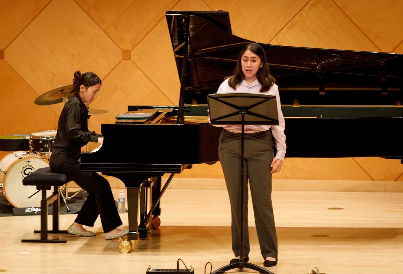 A student sings on a stage while another plays the piano, demonstrating the expertise gained in the BMUS in Performance (Collaborative Piano).