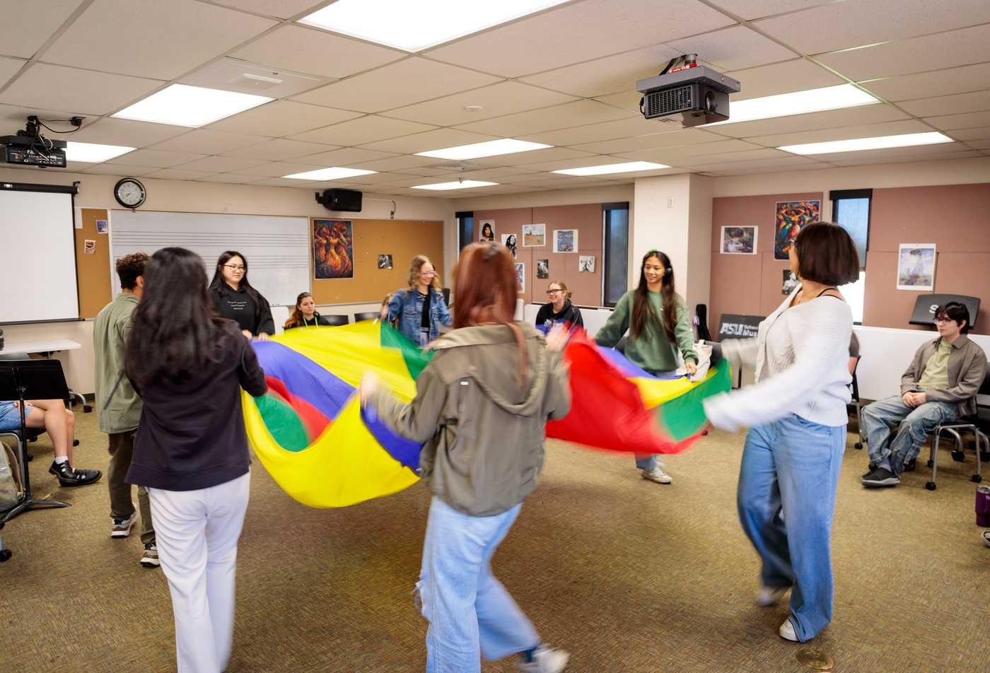Students participate in an interactive classroom activity with a parachute, demonstrating hands-on learning in the BMUS in Music Therapy.