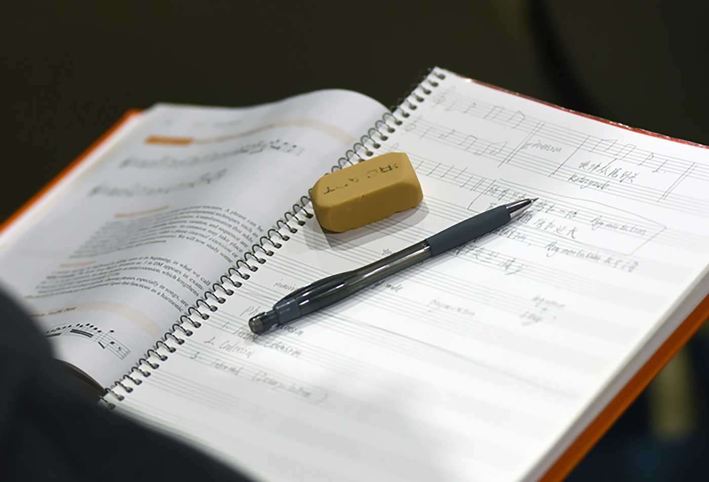 A student takes notes on a music sheet, showcasing the field explored in the BMUS in Theory and Composition (Theory).