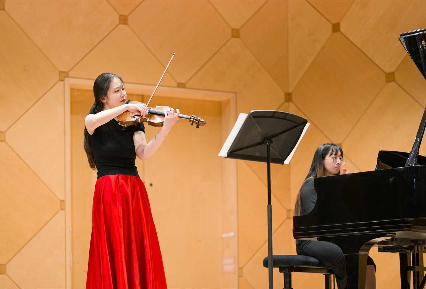 A violinist performs alongside a piano, showcasing the expertise gained in the Music Performance, MM.