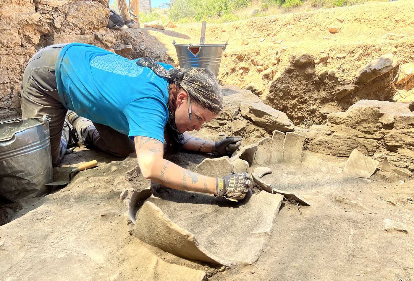 An art historian examines ceramic artifacts in the field, reflecting hands-on learning in the PhD in Art History.