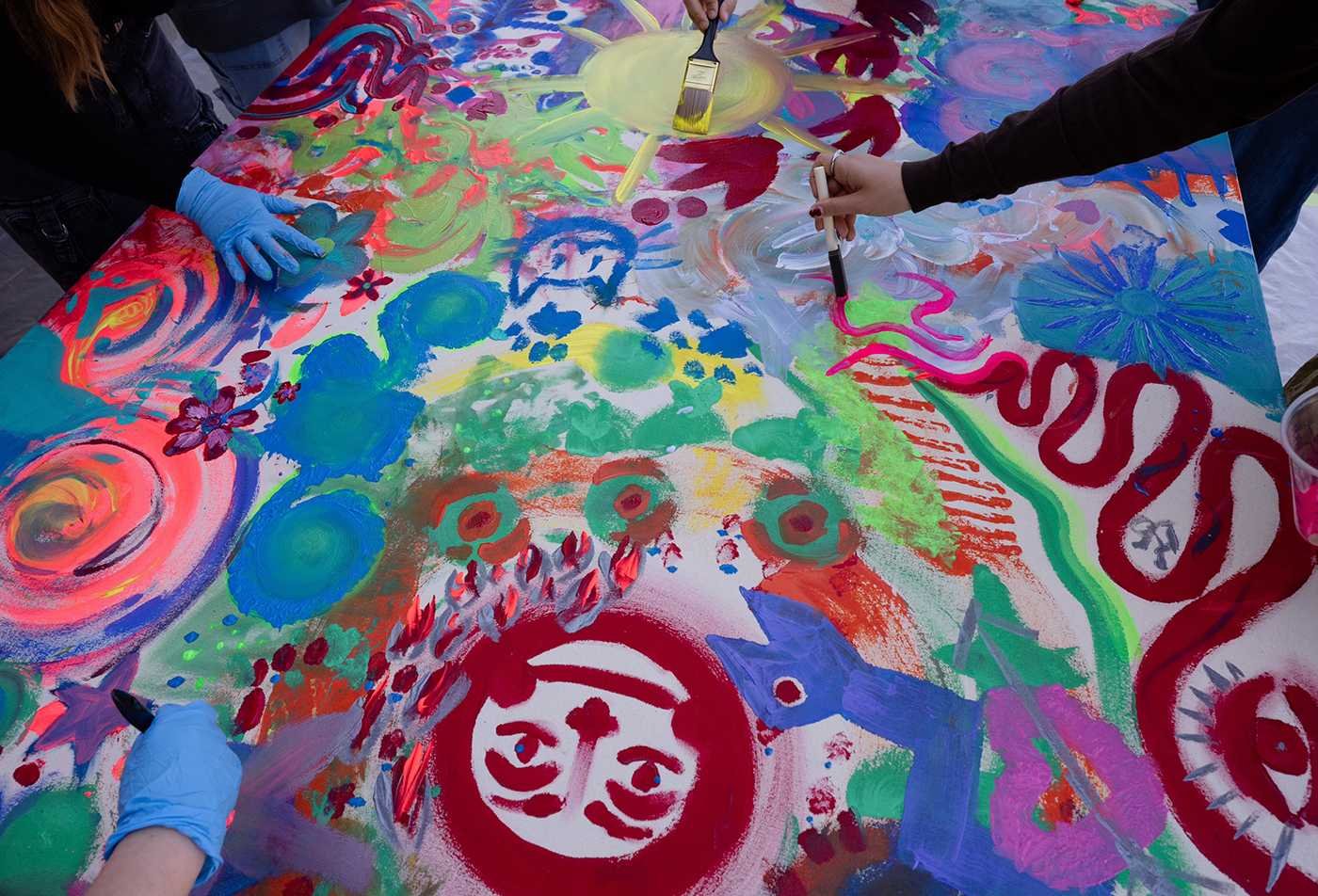 Students collaborate on large painted canvas, showcasing hands-on learning in the BFA in Art (Art Therapy)