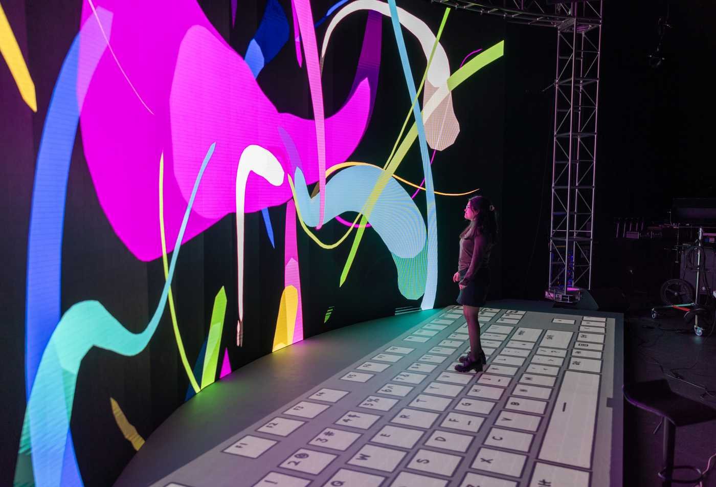 A student stands before a digital display of swirling colors, symbolizing the field of the Design (Experience Design), MSD.