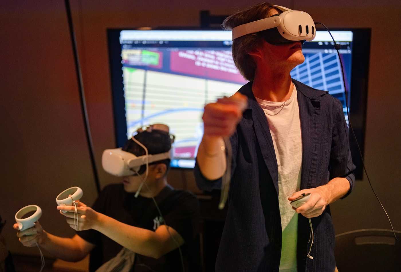 Two students explore a VR experience, demonstrating the field explored in the Media Arts and Sciences (Extended Reality Technologies), MS.
