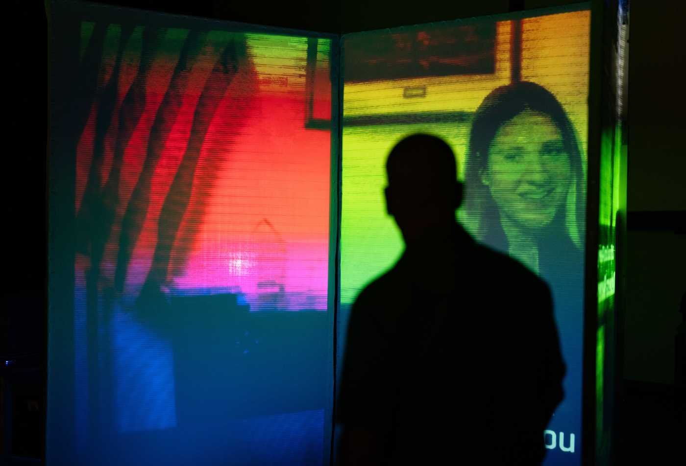 A silhouette watches a digital exhibit, demonstrating the field explored in BA in Media Arts and Sciences (Graphic Information Technology).