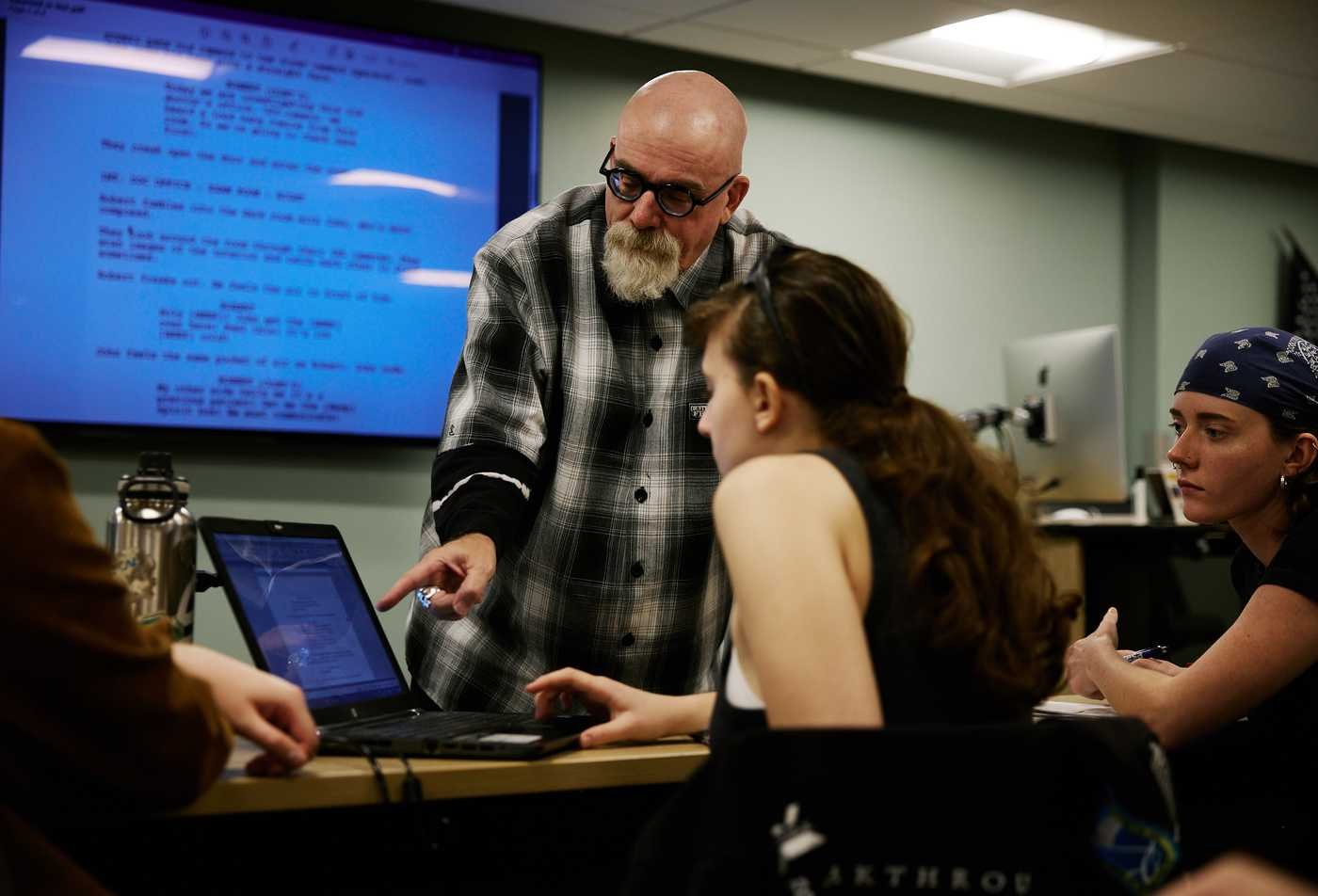 Students in a screenswriting classes recieve indivudal tips from the professor, demonstrating hands-on learning in the BFA in Film and Media Production (Screenwriting)