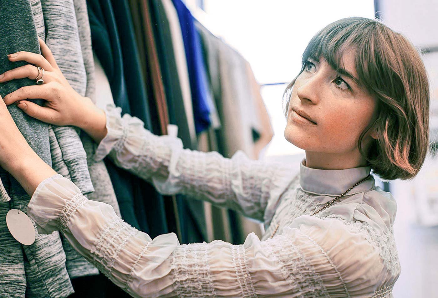 A student examines a row of coats, showcasing the field explored in the BA in Fashion (Merchandising).