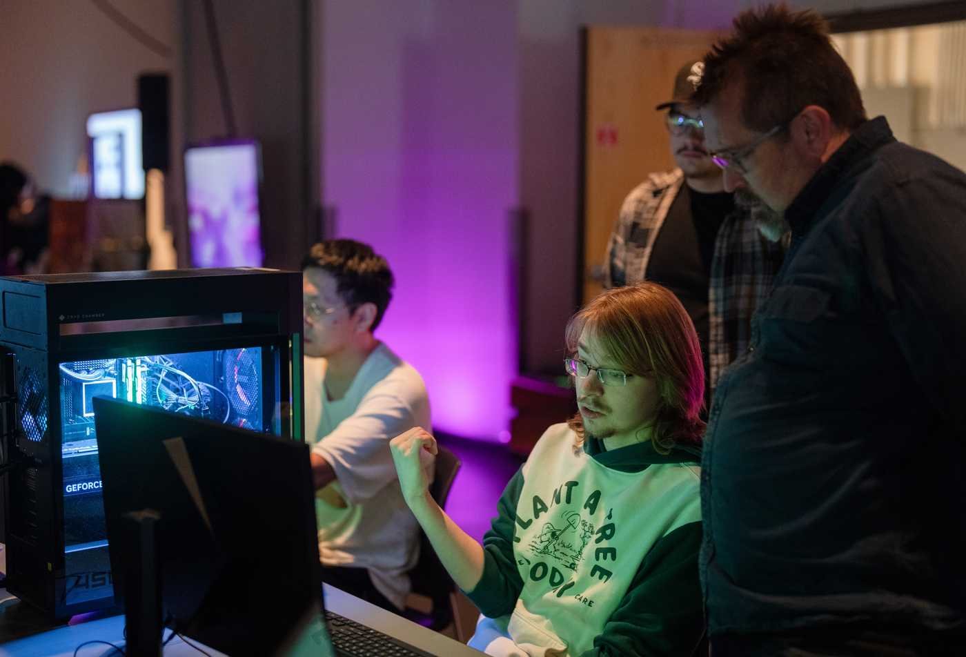 Students gather around a computer as they collaborate on a game together, showcasing hands-on learning in the BS in Game Studio Production.