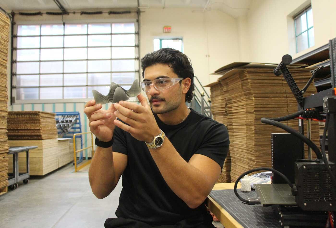 A student examines a 3D printed project, showcasing the field explored in the Industrial Design, MID.