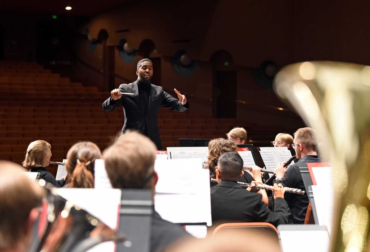 A conductor leads an orchestra, showcasing hands-on learning in the Performance (Conducting), MM.