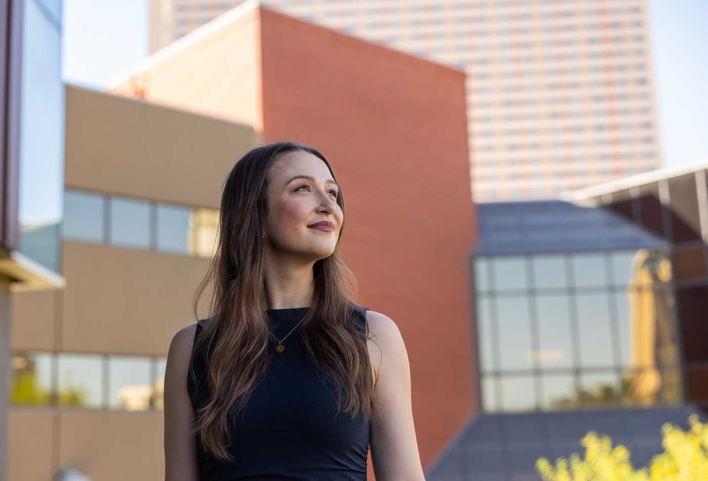 A young woman stands outdoors against a backdrop of the university campus, symbolizing leadership in the MS in Nutritional Science.