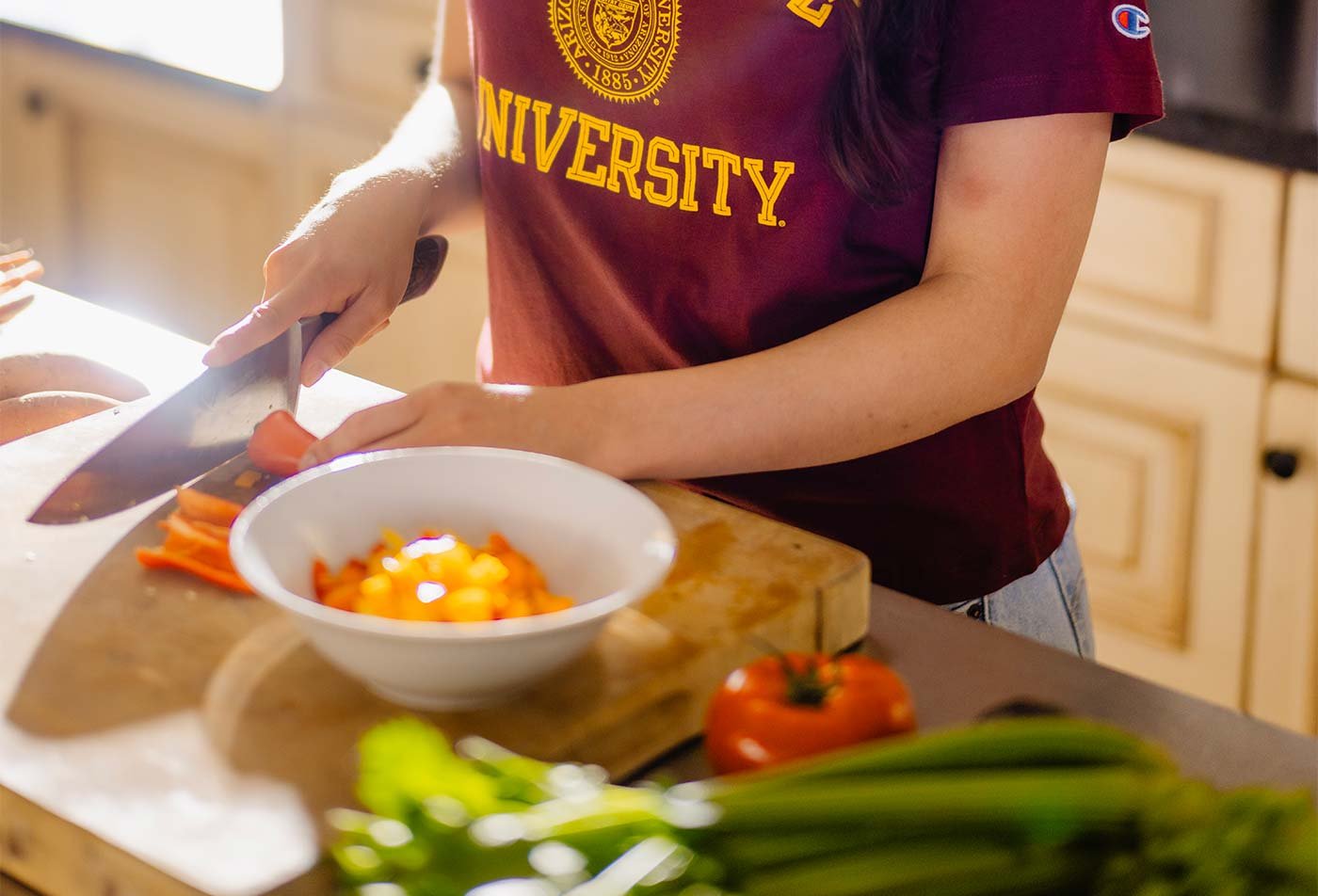 A student cuts vegetables in a bright kitchen, demonstrating the nutrition principles examined in the certificate in Nutrition Education and Counseling