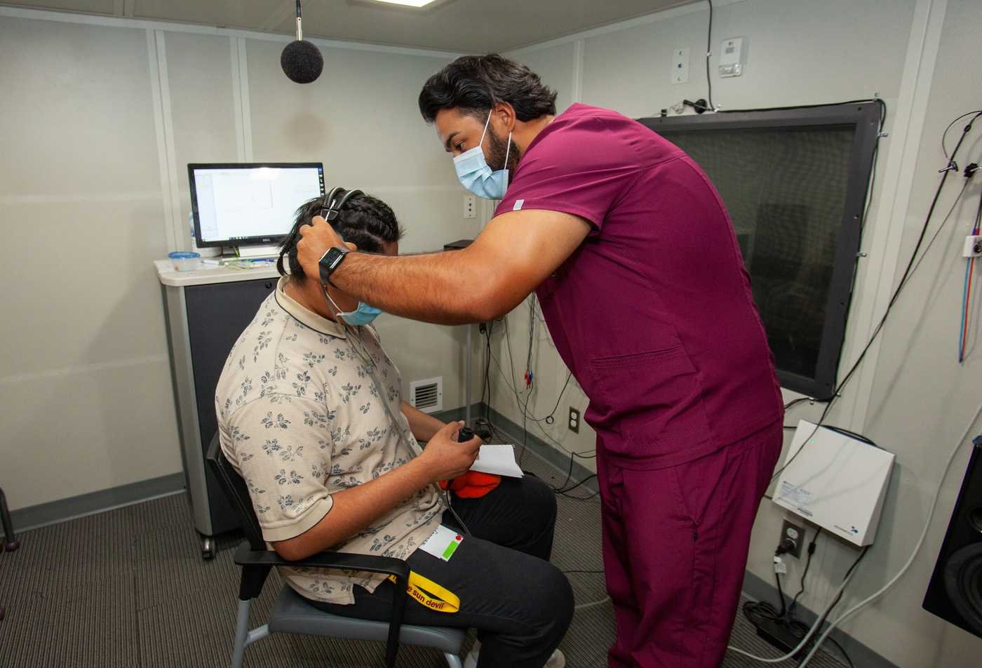 A researcher performs hearing tests on a participant, demonstrating field explored in the BS in Speech and Hearing Science