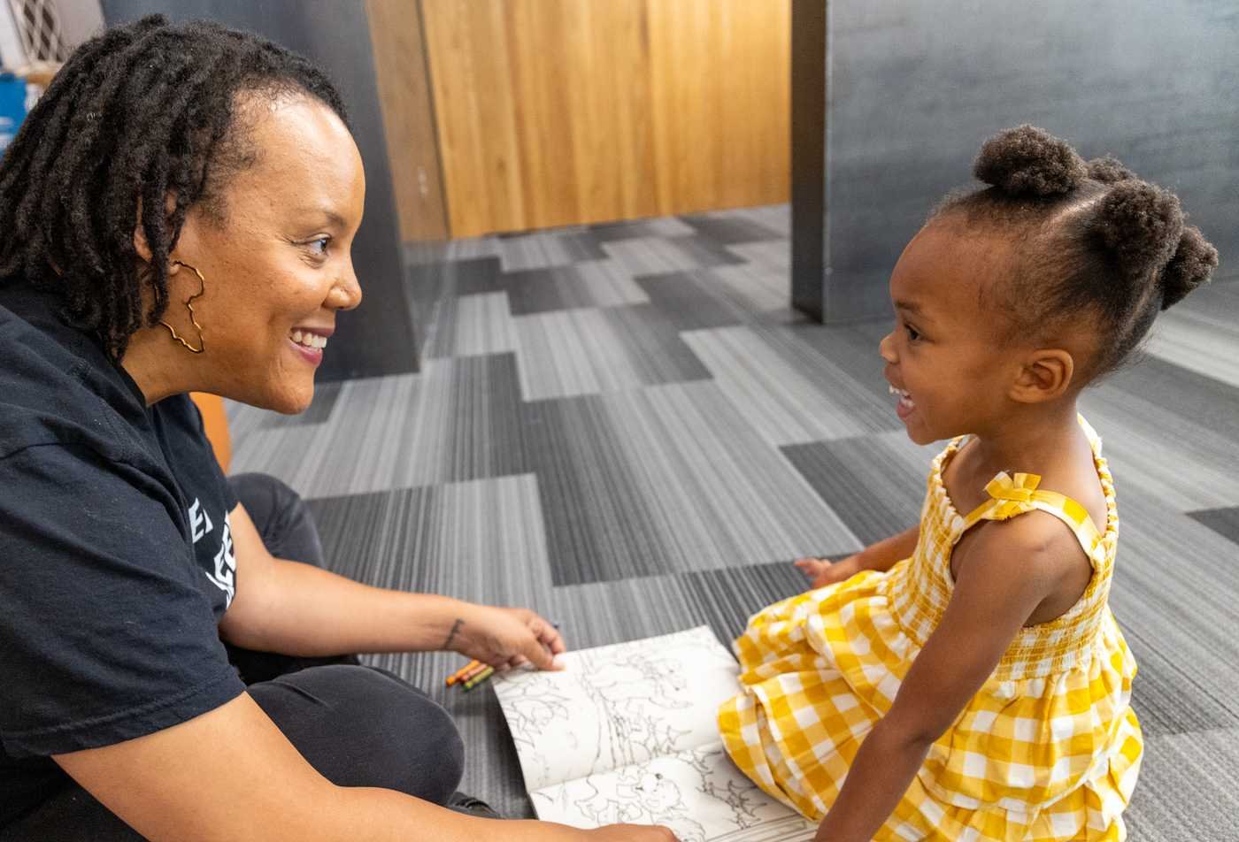 A student colors together with a young girl, demonstating the expertise gained in the certificate in Speech-Language Pathology Assistant.