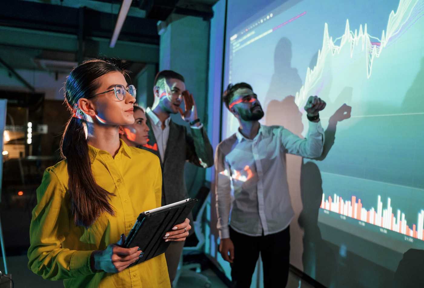A group of four professionals discusses data in a modern office, highlighting collaborative learning in the MS in Biostatistics.