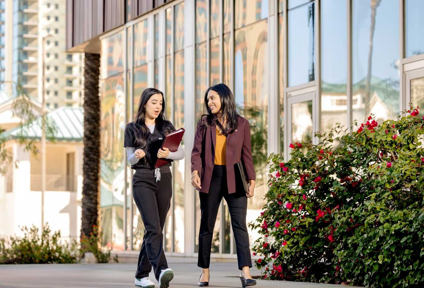 A health professional connects with a policy expert as they walk around campus, showcasing the expertise gained in the BS in Health Care Administration and Policy