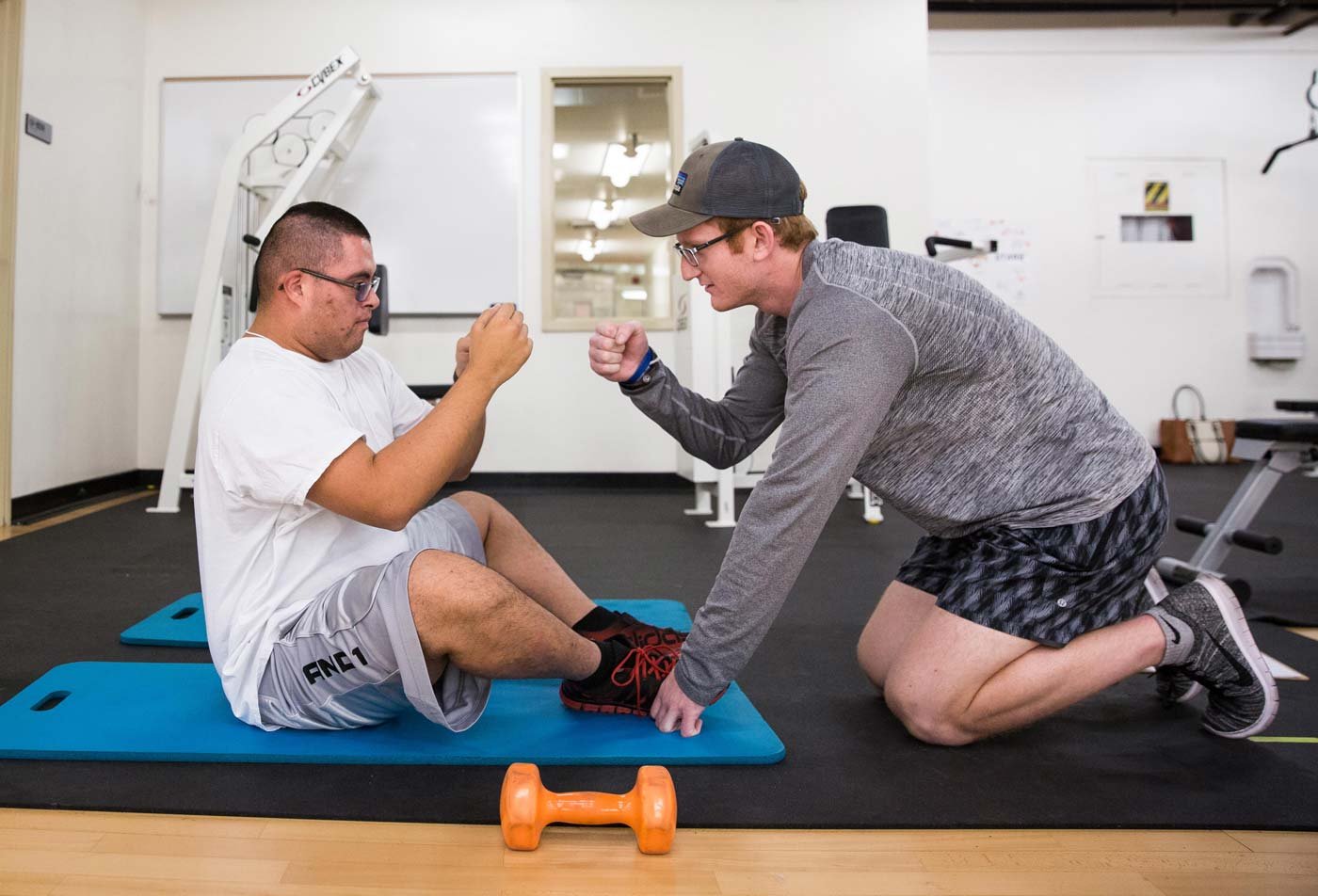 A student congratulates a client after a workout, demonstrating the principles and expertise gained in the certificate in Personal Fitness Training.