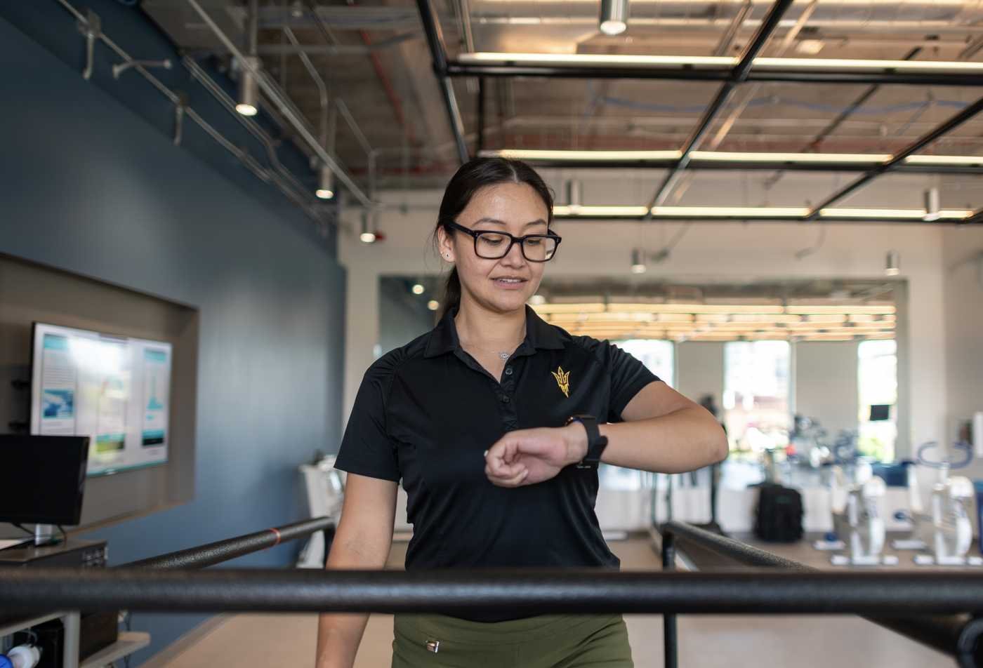 A student checks on her health data while she uses the treadmill, showcasing the practical field explored in the minor in Personal Health.