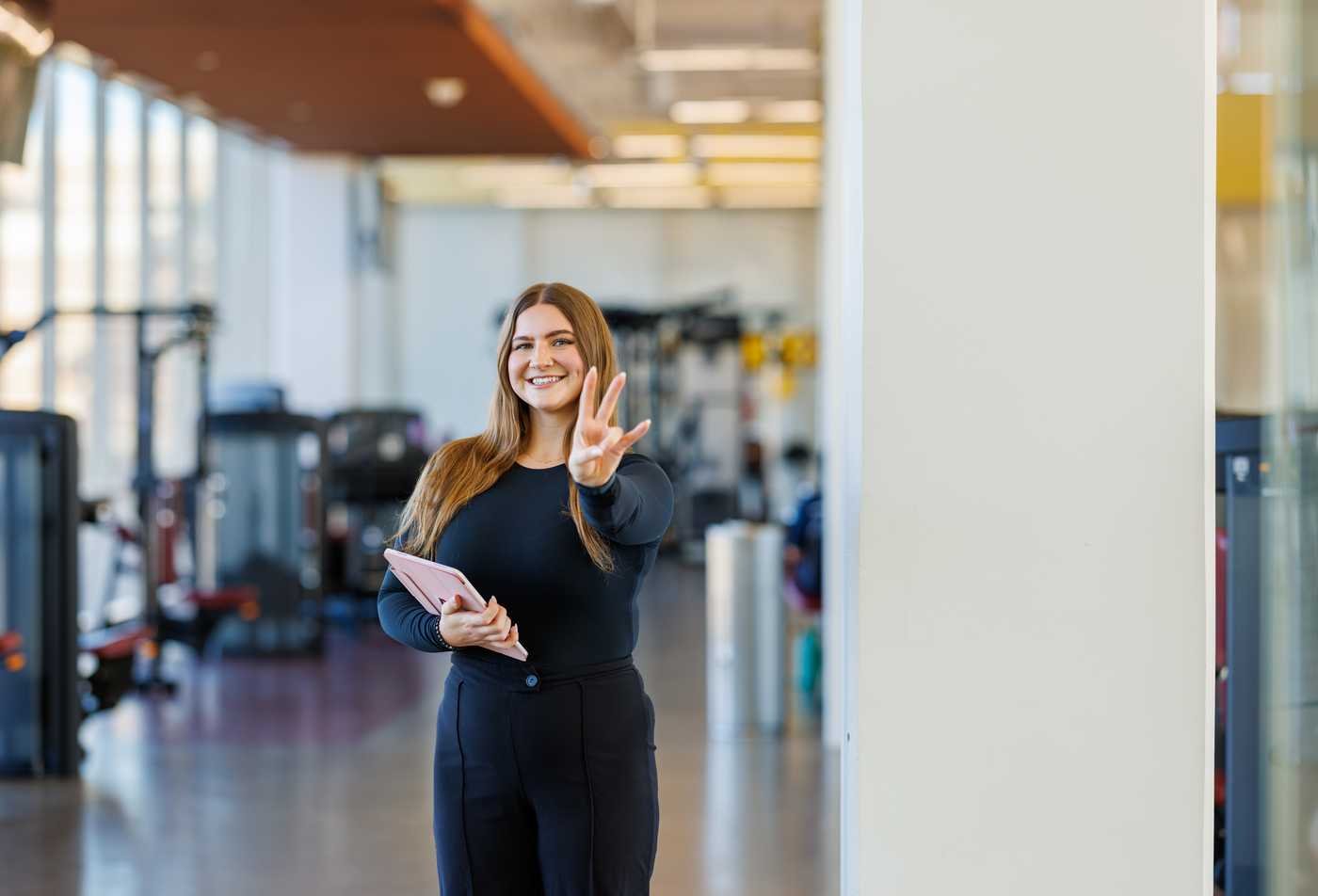 A student poses in a well-equipped gym, demonstrating the leadership gained in the MS in Population Health.