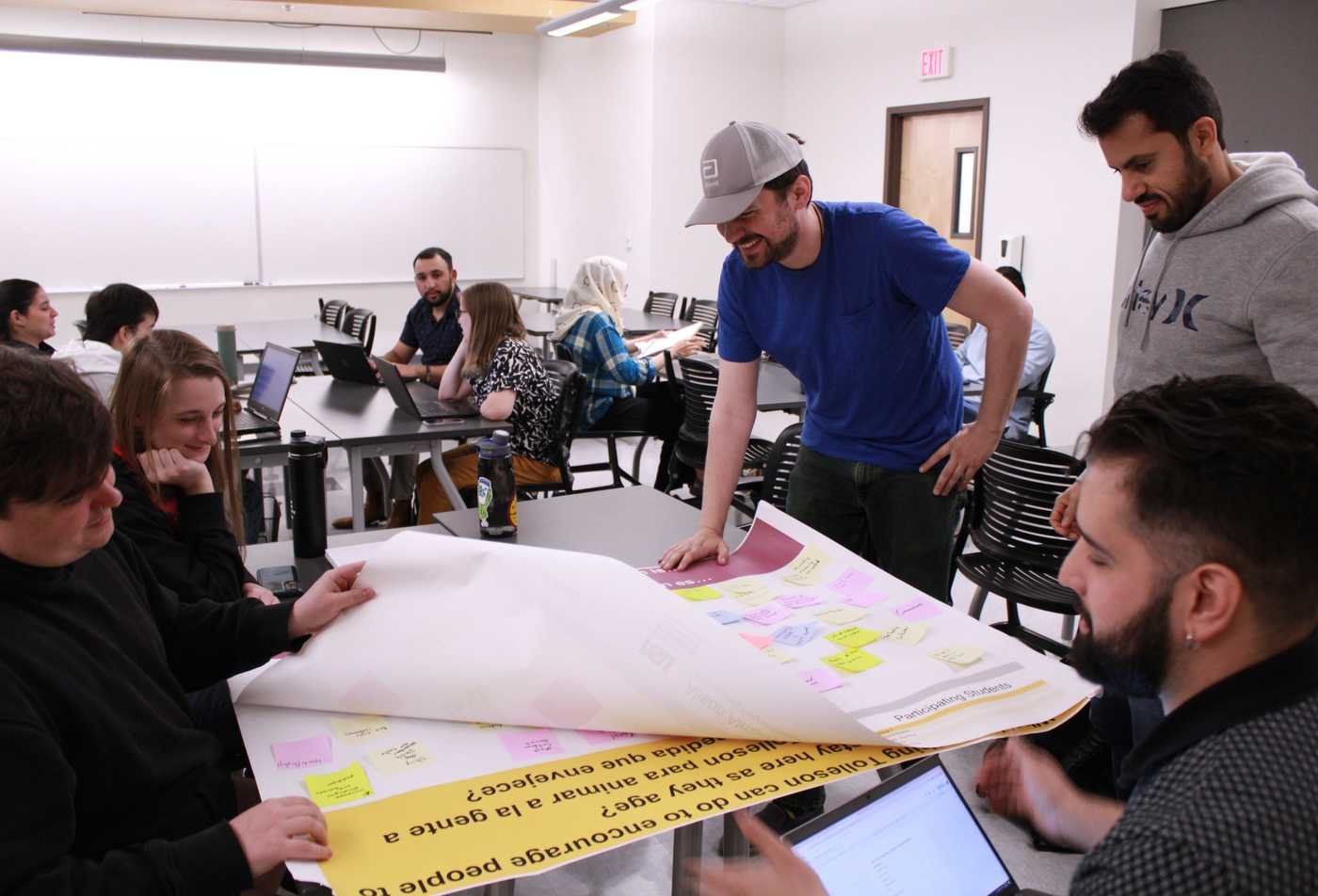 Urban planning students review a poster and sticky notes during a group workshop, showcasing collaborative learning in the Urban and Environmental Planning, MUEP.