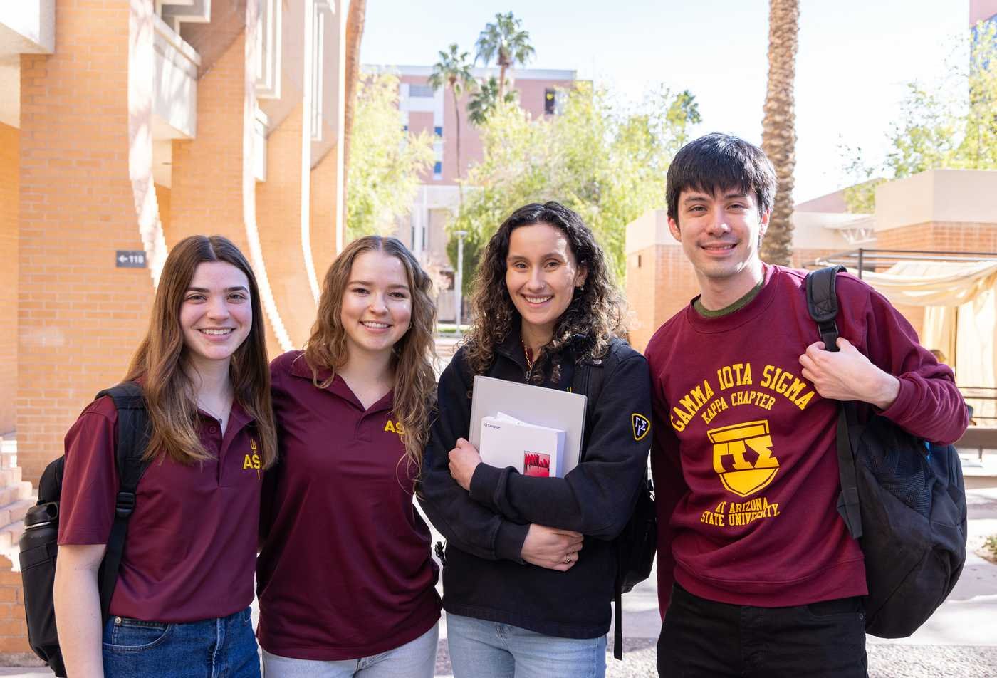 Four students stand together smiling on a sunny outdoor campus walkway, symbolizing the collaborative learning environment of the BS in Actuarial Science.