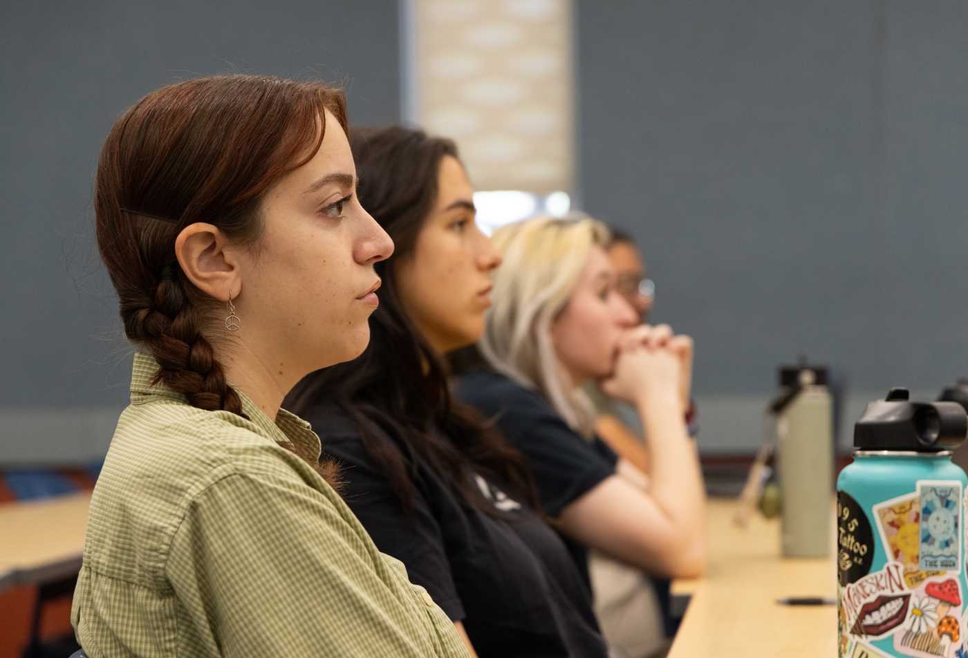 A student in an class actively listens to her professor, demonstrating focused learning in the MS in American Indian Studies (Cultural Resource Revitalization and Sust).