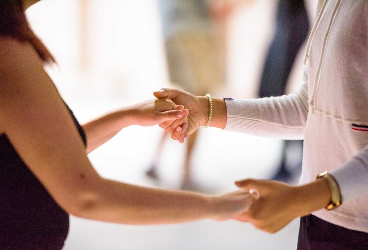 Two people hold hands, supporting each other, demonstrating the empathy cultivated in the certificate in Applied Prevention Science.