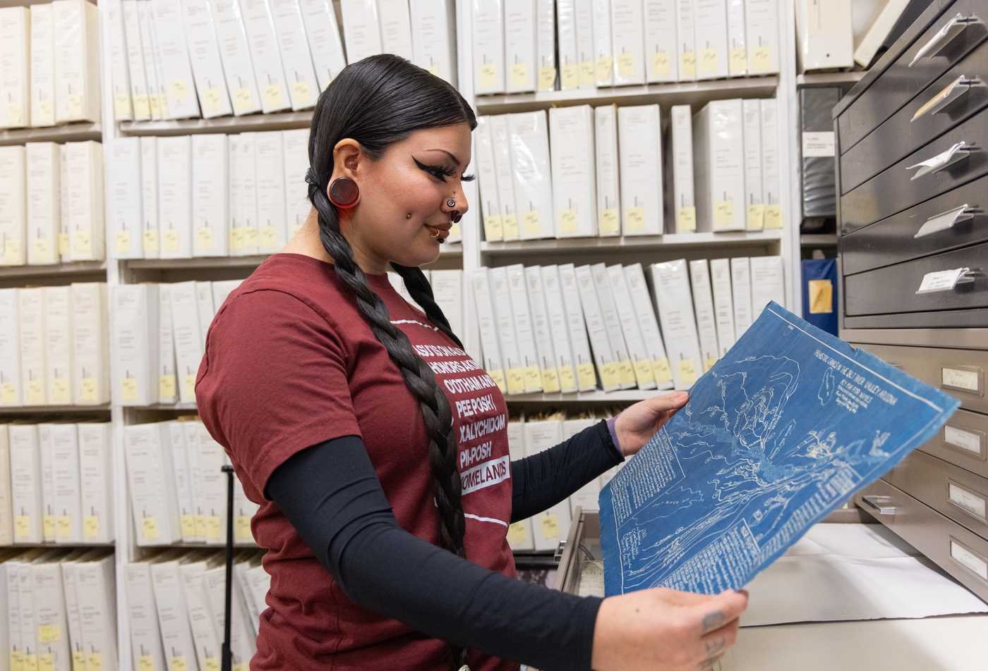 A female anthropology student examines a blue print of prehistoric canals, demonstrating hands-on learning in the BS in Anthropology.