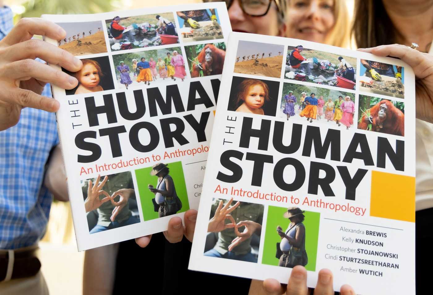 Professors hold up the cover of a book titled 'The Human Story: An Introducton to Anthropology', showcasing the field explored in the minor in Anthropology.
