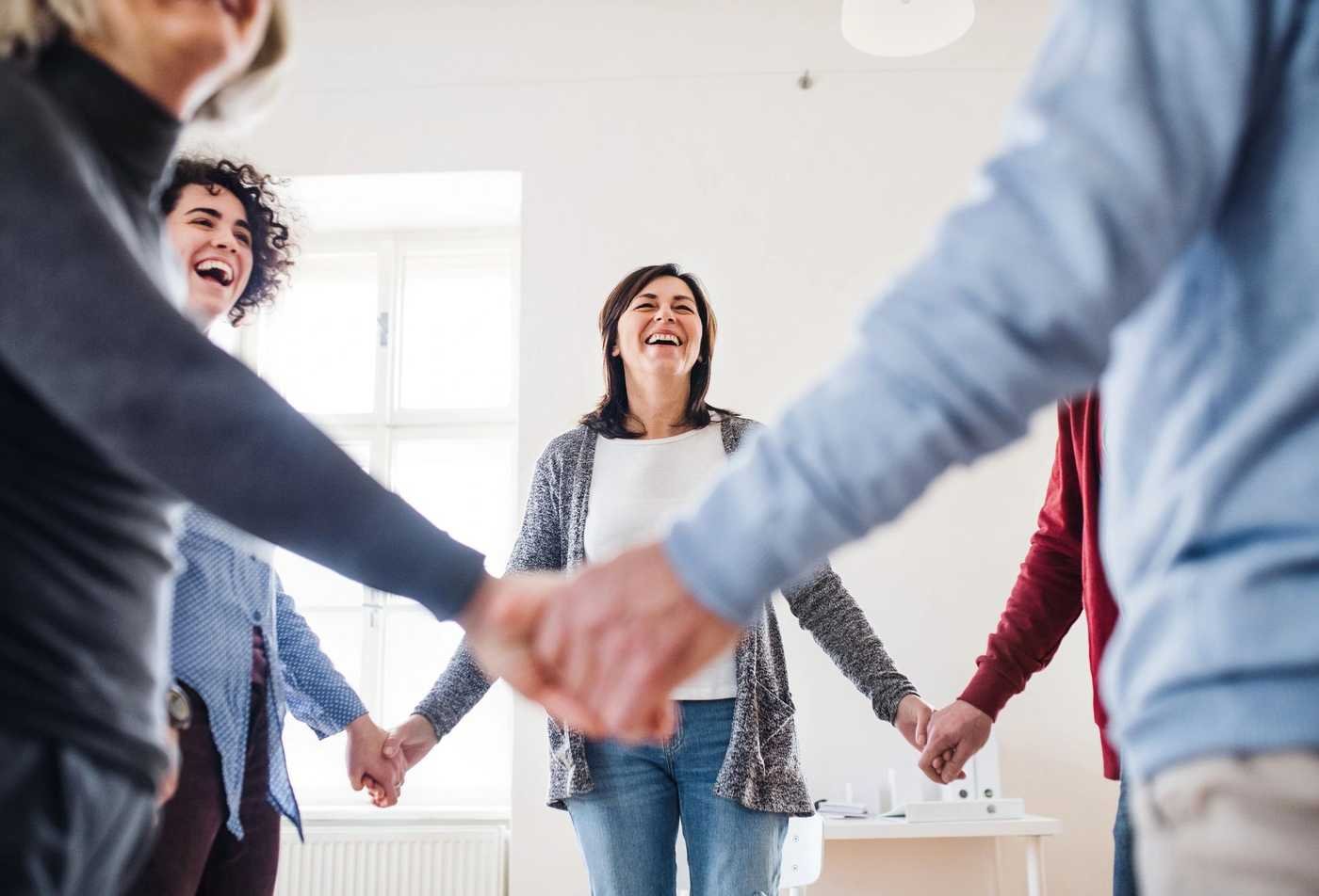 Participants of an addiction prevention support group grasp hands while standing in a circle, showcasing the field explored in the certificate in Addiction and Substance-Use Related Disorders.