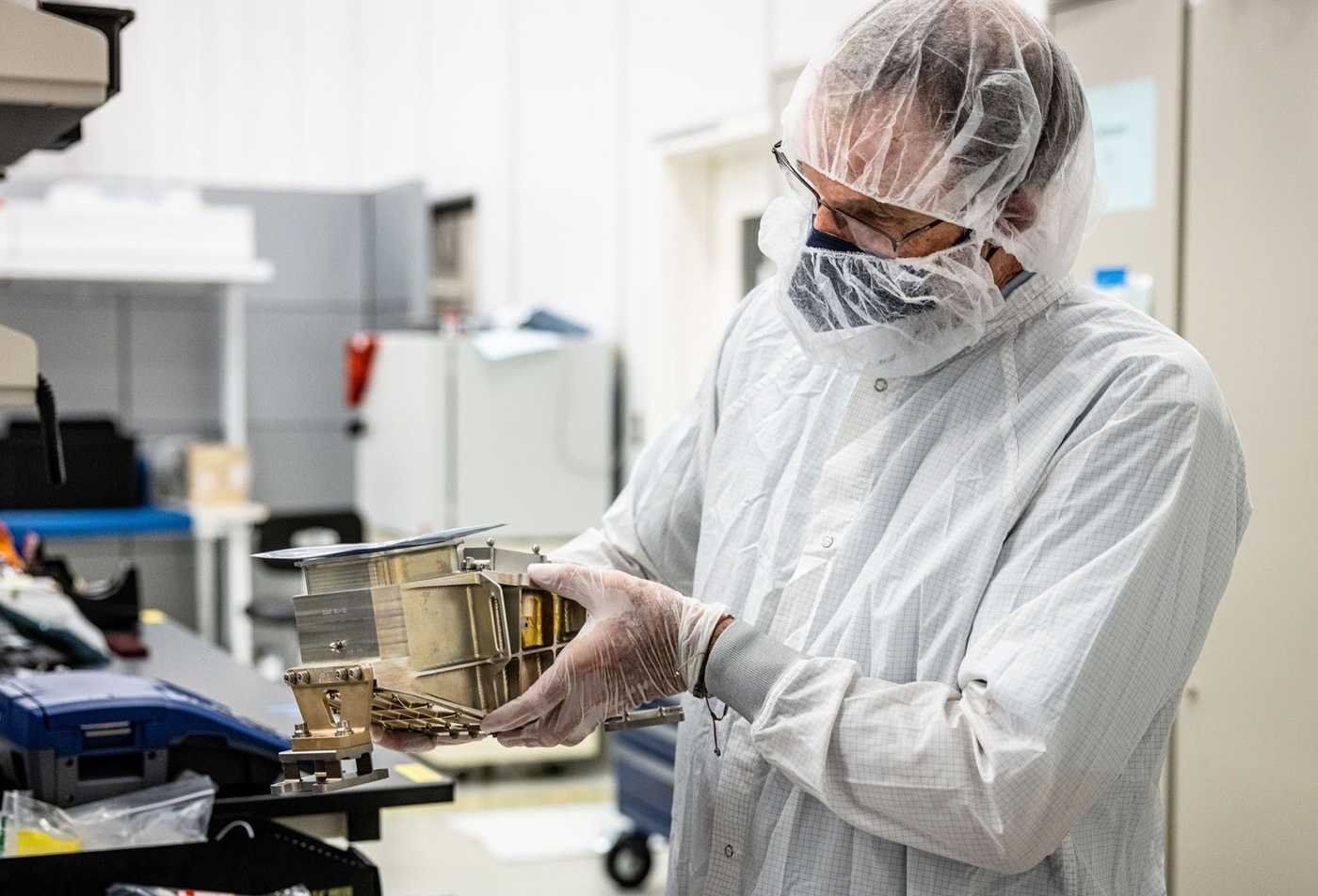 A researcher studies a piece a scientific instrument to analyze data, reflecting inquiry in ASU's Astronomical and Planetary Sciences (Astrophysics), BS program.