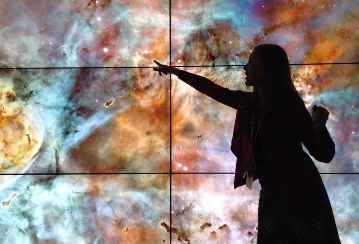 A researcher points to a vivid space image, exploring the cosmos in ASU's Astronomical and Planetary Sciences, BS program.